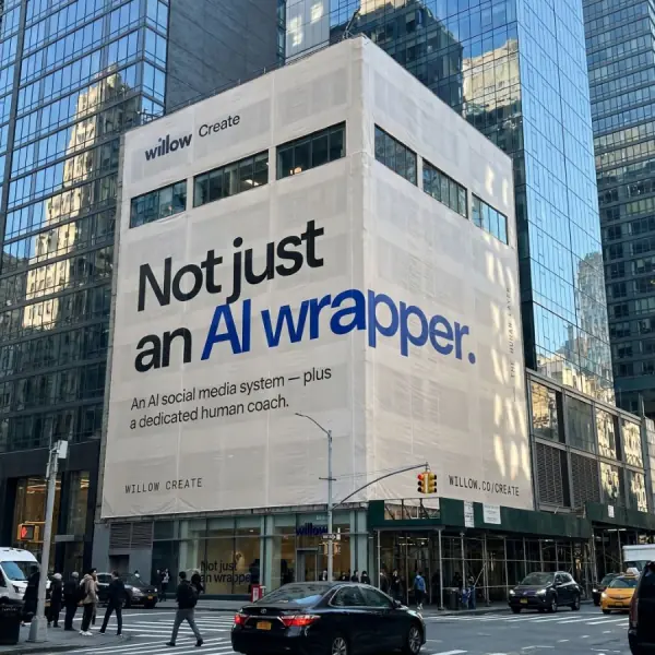 Willow Create building wrap reading 'Not just an AI wrapper — an AI social media system plus a dedicated human coach.'
