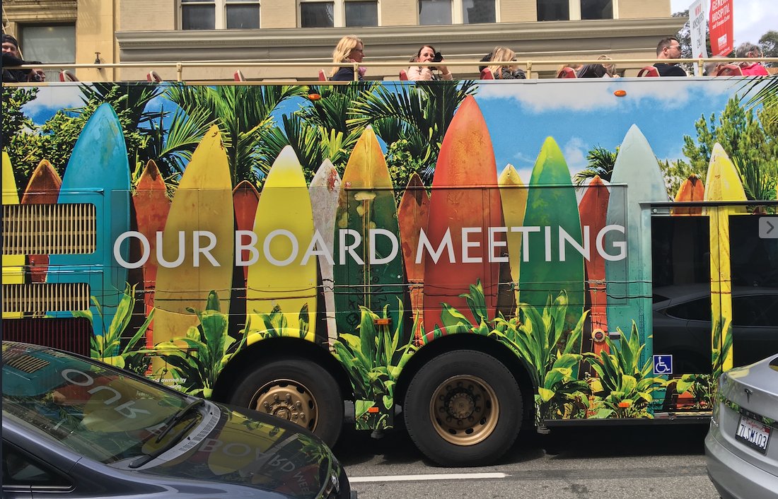 Een opentoeringbus met surfplanken en de tekst 'Our board meeting'