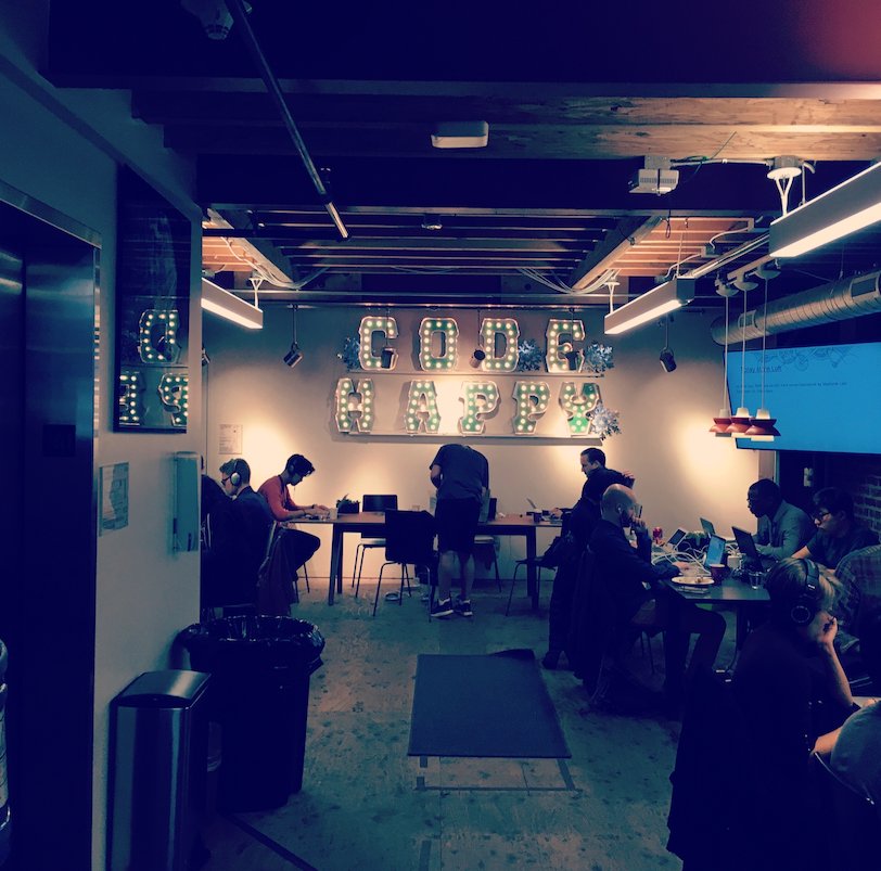 Een hackathonruimte met een verlicht 'Code happy'-bord