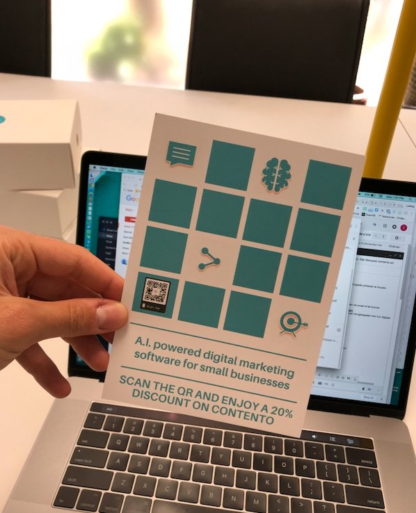 Een hand houdt een gedrukte marketingflyer met QR-code vast